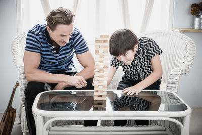 Father and son playing with wooden blocks at home