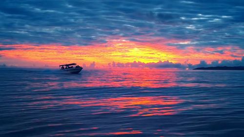 Boat sailing in sea against sky during sunset