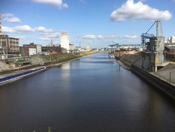 Bridge over river amidst buildings in city against sky