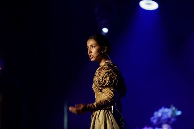 Side view of young woman looking at illuminated stage