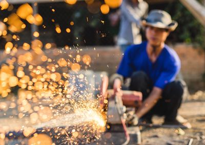 Sparks emitting from metal against worker working at construction site