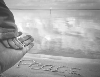 Close-up of hands against sea