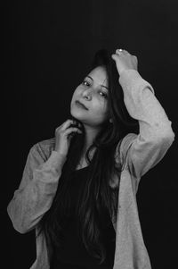 Young woman standing against black background