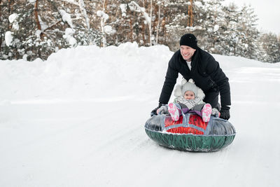 Joyful dad rides his daughter on a sleigh in the snowy forest. high quality photo