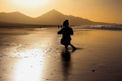 Full length of man on beach against sky during sunset