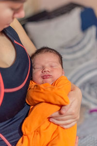 Young mother holding her sleeping newborn baby in her arms