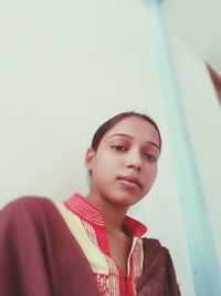 Portrait of beautiful young woman against wall