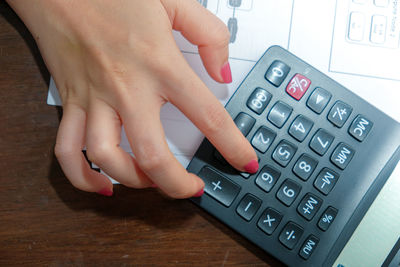 High angle view of hands holding camera on table