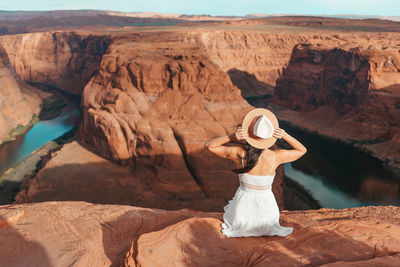 Rear view of woman sitting on rock formations