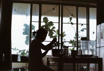 Rear view of man standing by window