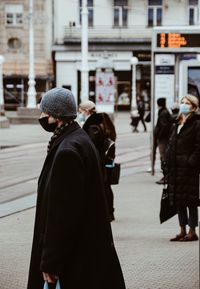 Rear view of people walking on street in city