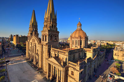 Panoramic view of buildings in city against clear blue sky