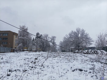 Snow covered field by buildings against sky