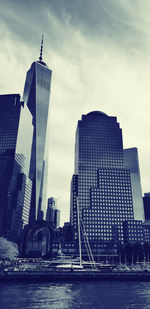 Modern buildings by river against sky in city