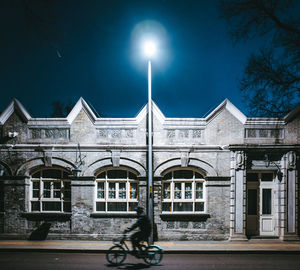 Bicycle by building against sky at night