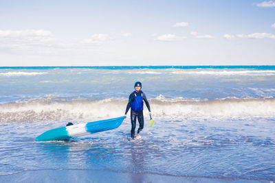 Rear view of woman swimming in sea against sky