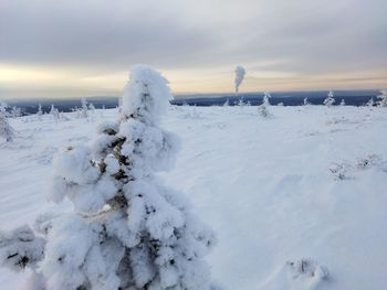 Snow covered land against sky during sunset