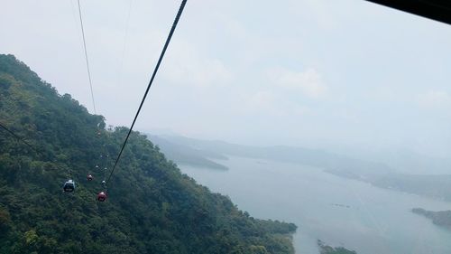 Overhead cable car over mountains against sky