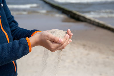 Midsection of person hand on beach