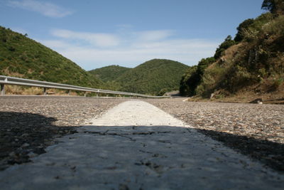Surface level of road by mountain against sky