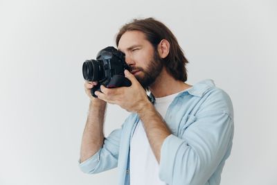 Man photographing against white background