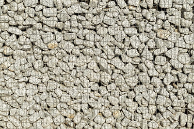 Stone wall in wire frame. textured background of a stone wall with iron netting.