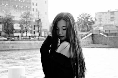 Young woman looking away while standing against buildings
