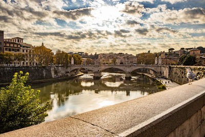 Arch bridge over river against buildings in city