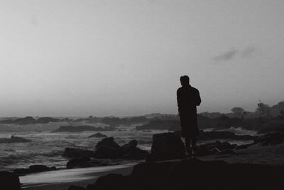 Silhouette man looking at sea against sky