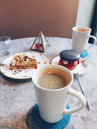 Cup of coffee and cups on table