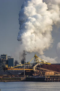 River by factory against sky