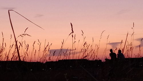 Silhouette people standing on land against sky during sunset