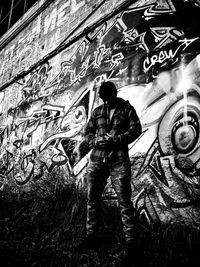 Full length of man standing against graffiti wall