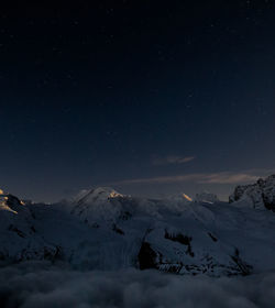 Scenic view of snowcapped mountains against sky at night