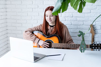 Portrait of young woman using laptop while sitting on sofa at home