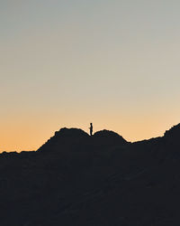 Silhouette of person standing on hill at sunset