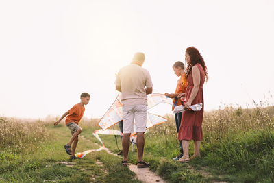Happy family and children run on meadow with a kite in the summer on the nature.