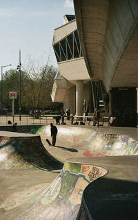 People skateboarding in city against sky