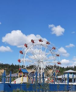 Low angle view of ferris wheel against cloudy sky