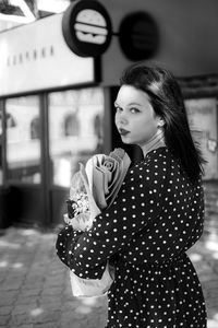 Young woman looking away while standing in city