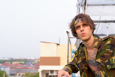 Portrait of young man looking away against sky