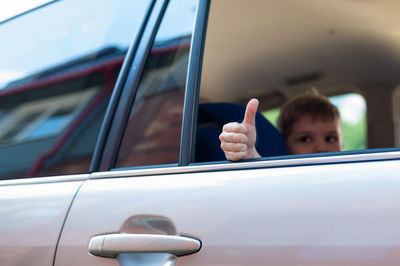 Boy gesturing while sitting in car