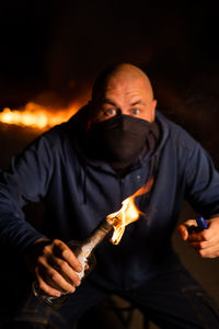 Midsection of man holding sparkler at night