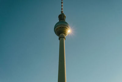 Low angle view of communications tower against clear blue sky