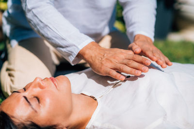 Woman in reiki spiritual healing session. reiki therapist holding hands above heart chakra