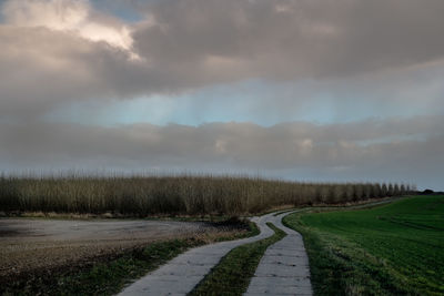 Road amidst field against sky