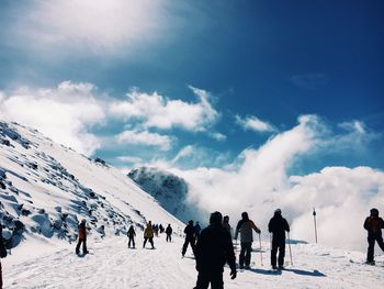 Group of people on snowcapped mountain against sky
