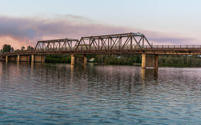 Arch bridge over river against sky during sunset