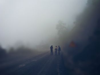Rear view of people walking on road in foggy weather