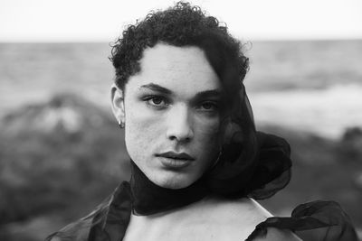 Young male with  androgynous look shot outdoor in black and white with rocks in background.